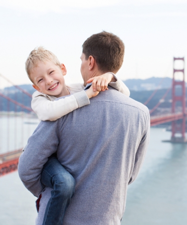 Man holding his son by the Golden Gate Bridge - a San Francisco Attraction