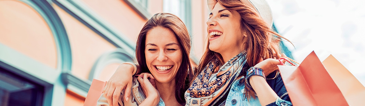 Young friends laughing and holding shopping bags