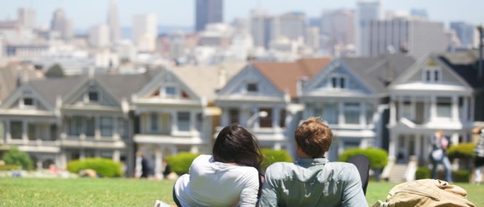 Couple relaxing on a hill in San Francisco overlooking a row of houses