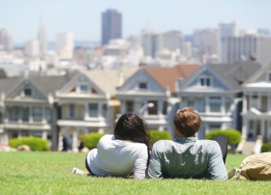 Couple relaxing on a hill in San Francisco overlooking a row of houses