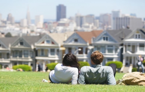 Couple relaxing on a hill in San Francisco overlooking a row of houses