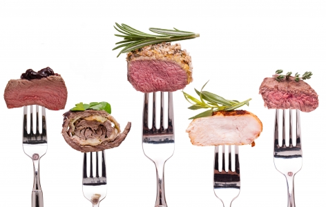 A line of forks with small bites of gourmet food